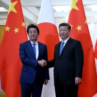 Prime Minister Shinzo Abe shakes hands with Chinese leader Xi Jinping in Beijing in December 2019.  | POOL / VIA REUTERS
