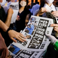 An extra edition of the Yomiuri Shimbun newspaper reporting on the death of former Prime Minister Shinzo Abe is handed out in Tokyo on Friday. | REUTERS