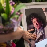 People line up to place flowers at a makeshift memorial outside Yamato-Saidaiji Station in Nara, where former Prime Minister Shinzo Abe was shot on Friday. | AFP-JIJI