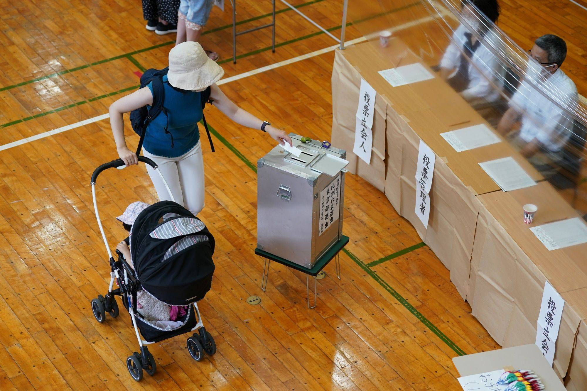 A voter casts a ballot in Sunday's Upper House election at a polling location in Tokyo's Minato Ward. | BLOOMBERG