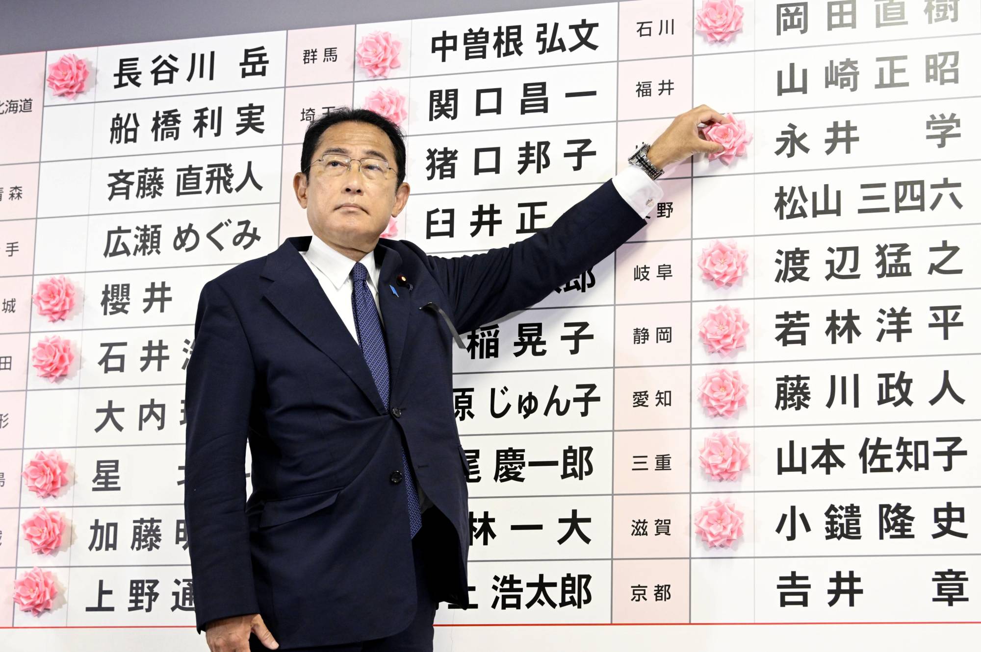 Prime Minister Fumio Kishida places a flower next to the name of a winning Liberal Democratic Party candidate at the party's headquarters in Tokyo on Sunday. | KYODO