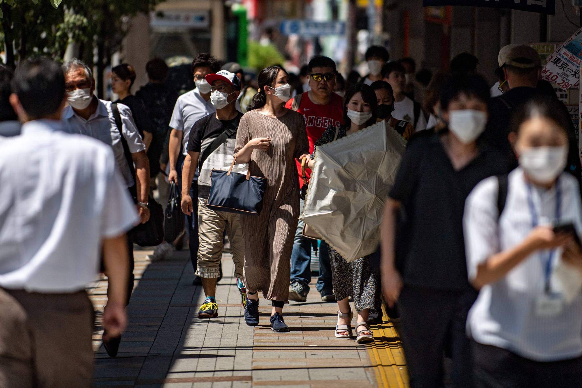 Pedestrians walk through Tokyo's Shinjuku district on June 28. | AFP-JIJI