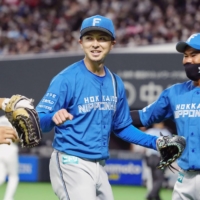 Fighters pitcher Naoyuki Uwasawa (left) returns to the dugout after the seventh inning of his team\'s game against the Lions in Sapporo on Saturday. | KYODO
