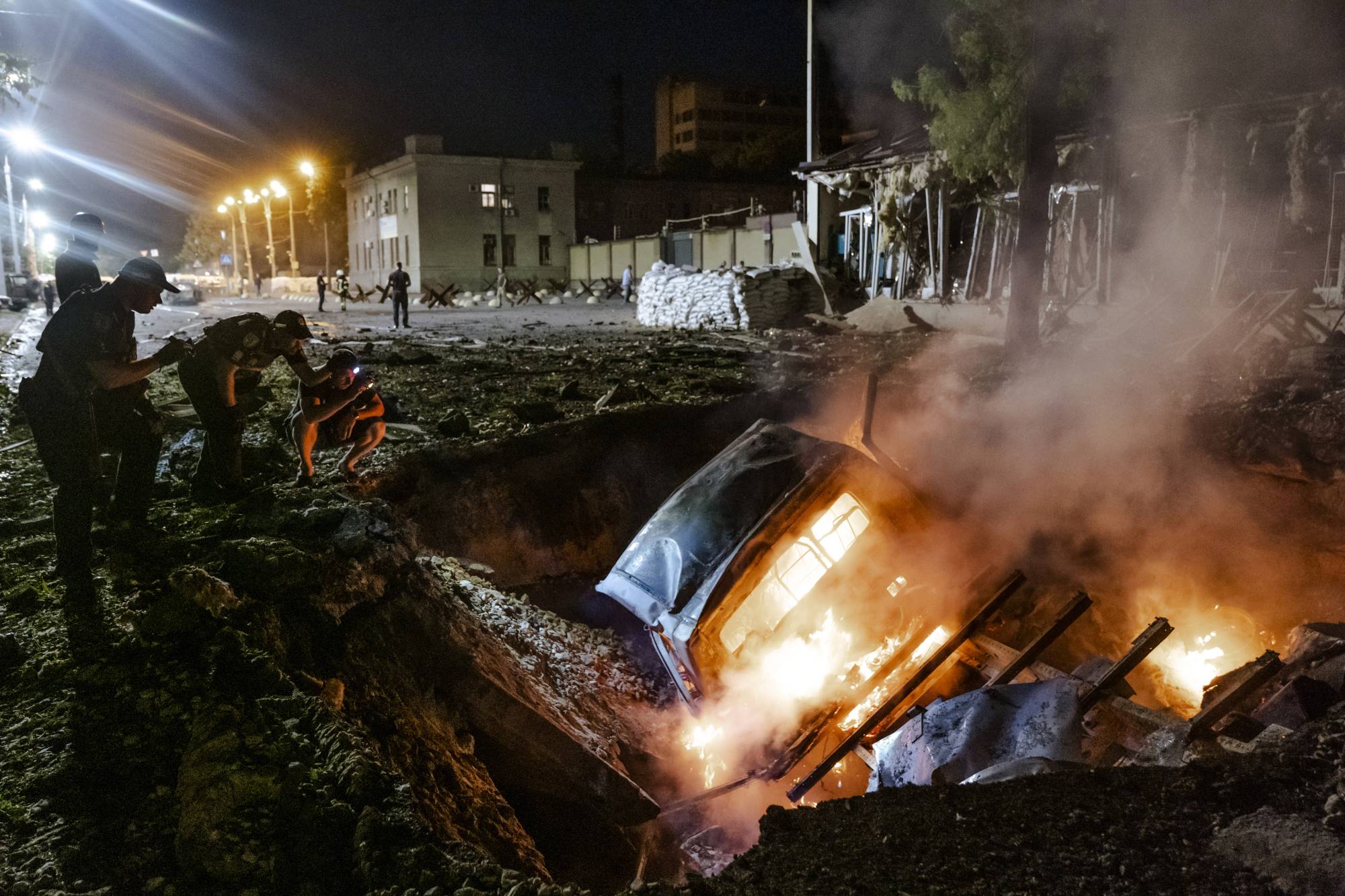 The wreckage of a car burns in a crater after a Russian missile strike in Dnipro, in central Ukraine, on Friday. Indiscriminate Russian attacks on civilian areas have become a hallmark of its invasion, and this week, an international conference in The Hague sought to coordinate an approach to the overwhelming allegations of war crimes in Ukraine. | Daniel Berehulak / The New York Times