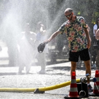A man cools down with water hoses in the city of Cologne, western Germany, as many parts of Europe experience a heat wave. | AFP-JIJI