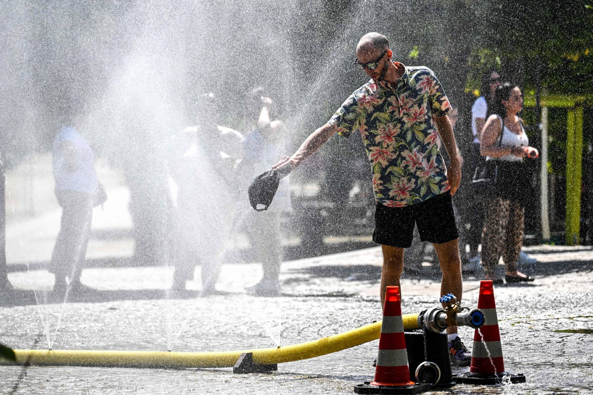 A man cools down with water hoses in the city of Cologne, western Germany, as many parts of Europe experience a heat wave. | AFP-Jiji