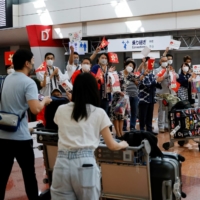 Representatives of Japanese shopping and tourism companies greet a group of tourists from Hong Kong upon their arrival at Haneda Airport on June 26. | REUTERS