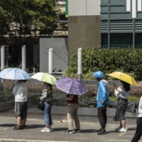 Pedestrians shelter from the sun under umbrellas in Shanghai on July 14. | BLOOMBERG