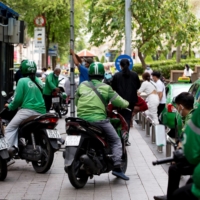 Grab riders and taxi drivers in Ho Chi Minh City in May 2021. There has been little discussion of how riders and drivers — who often work long hours, waiting at street corners and outside restaurants for orders, and have limited access to medical care — are dealing with extreme weather. | BLOOMBERG