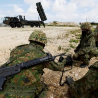 Ground Self-Defense Force members conduct a military drill next to an anti-ship missile unit on Miyako Island, Okinawa Prefecture, in April. | REUTERS