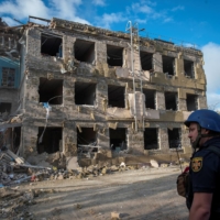 A rescuer stands in front of a school building destroyed by a Russian missile strike in Kramatorsk, Ukraine, on Thursday. | REUTERS