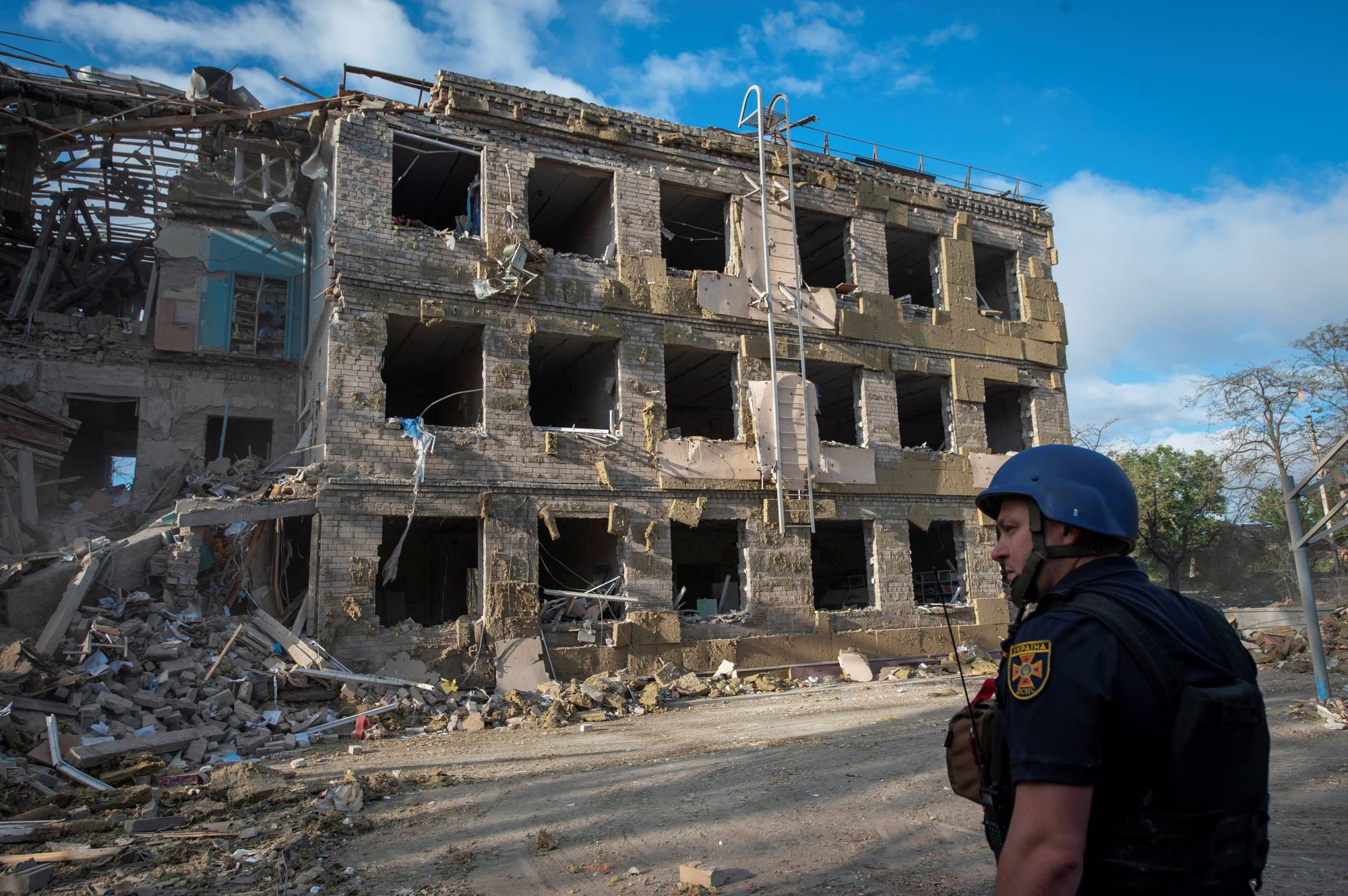 A rescuer stands in front of a school building destroyed by a Russian missile strike in Kramatorsk, Ukraine, on Thursday. | Reuters