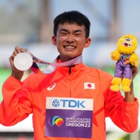 Silver medalist Masatora Kawano celebrates on the podium after the men\'s 20-km race walk at the World Athletics Championships in Eugene, Oregon, on Sunday. | REUTERS