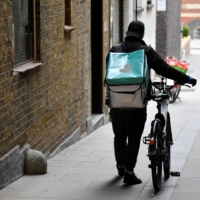 A Deliveroo delivery rider pushes a bicycle in London in 2021.  | REUTERS