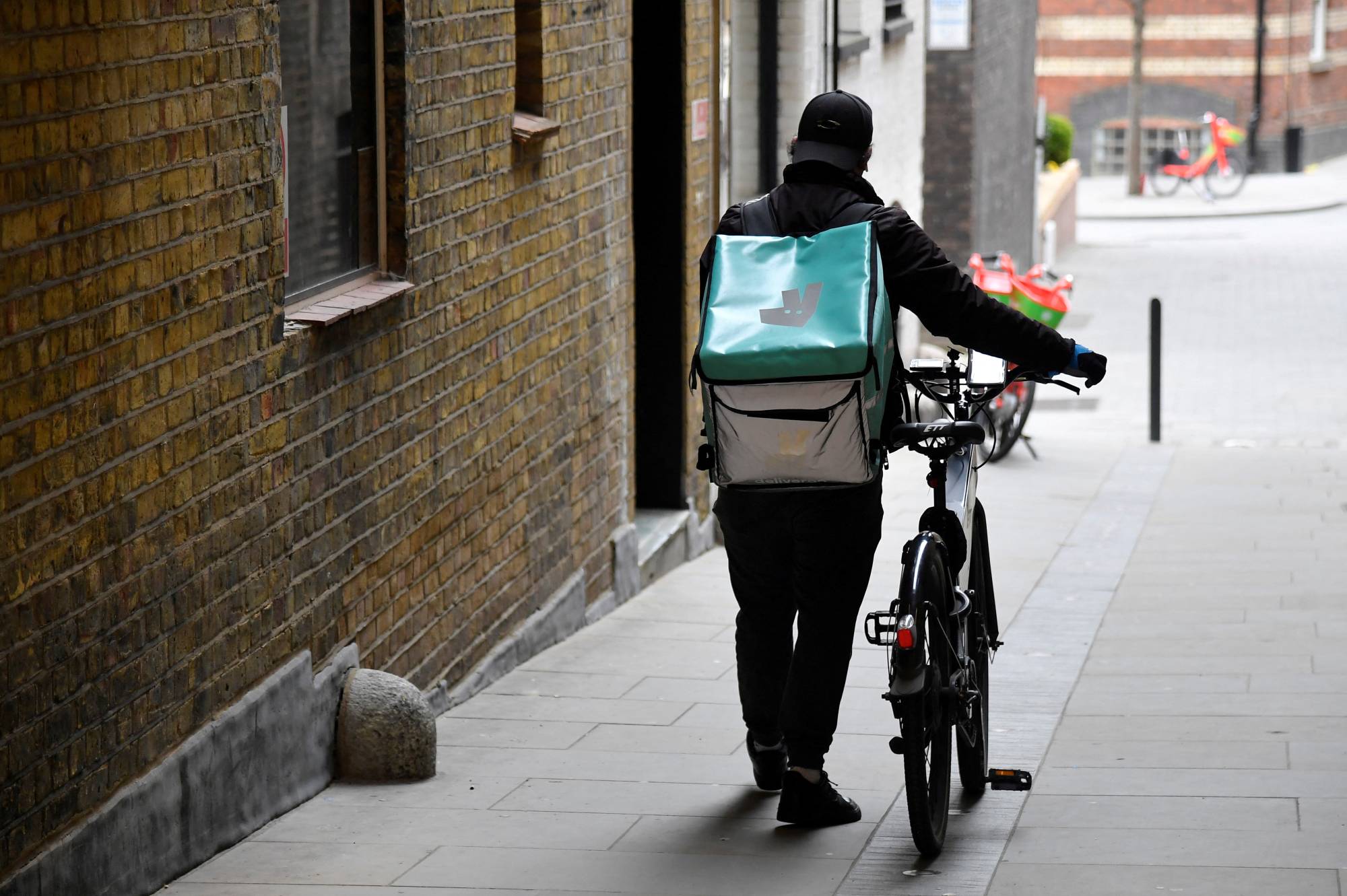 A Deliveroo delivery rider pushes a bicycle in London in 2021. | REUTERS