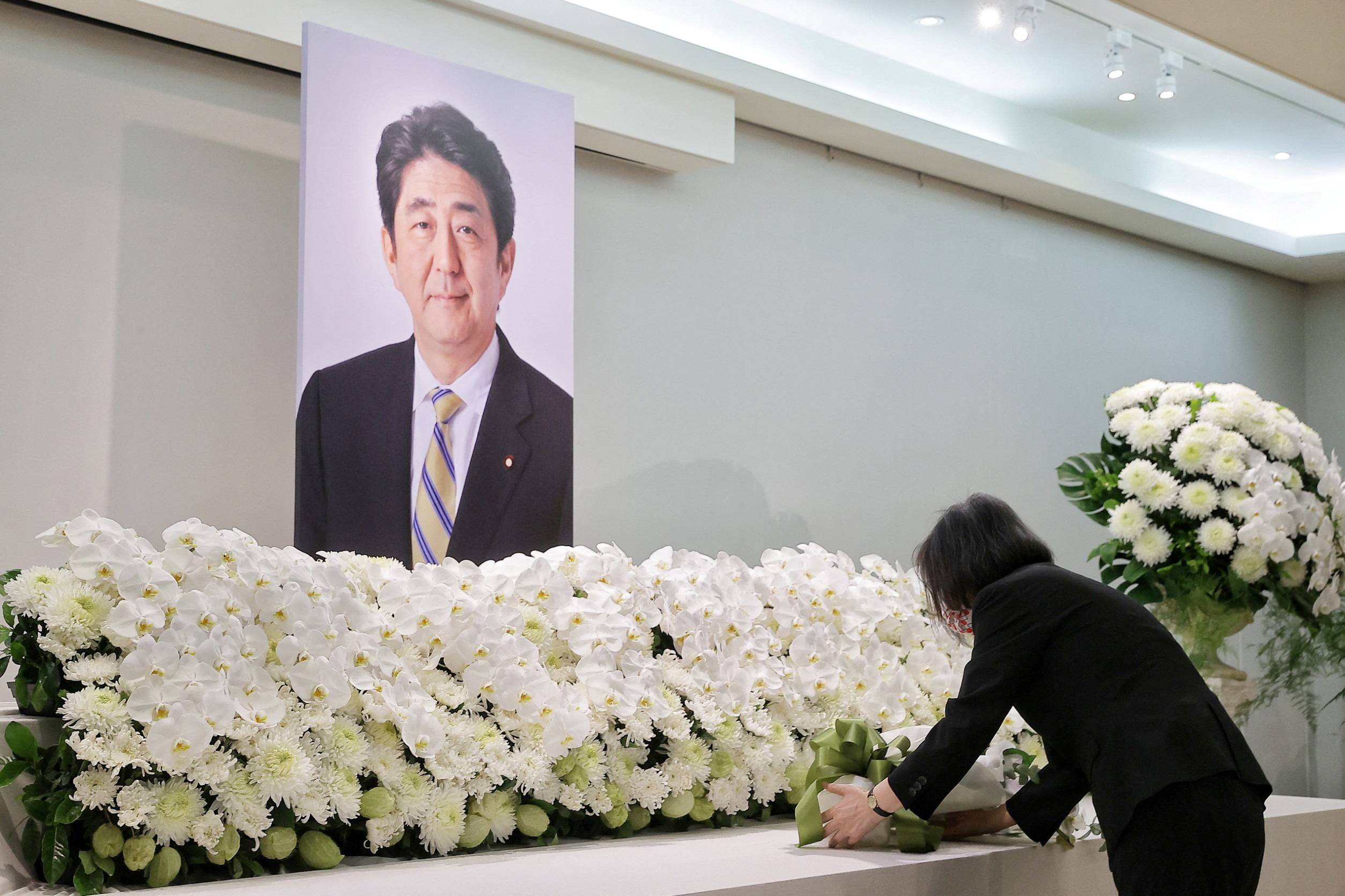 Taiwanese President Tsai Ing-wen lays flowers in front of a portrait of former Japanese Prime Minister Shinzo Abe at the Japan-Taiwan Exchange Association office in Taipei on July 11. | TAIWAN PRESIDENTIAL OFFICE / VIA REUTERS