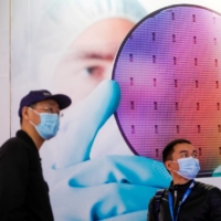People visit a display of semiconductor device at Semicon China, a trade fair for semiconductor technology, in Shanghai on March 17, 2021 | REUTERS