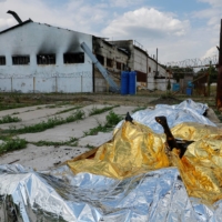Burnt bodies of detainees lie covered following the shelling at a pre-trial detention center in Olenivka, Ukraine, on Friday.  | REUTERS