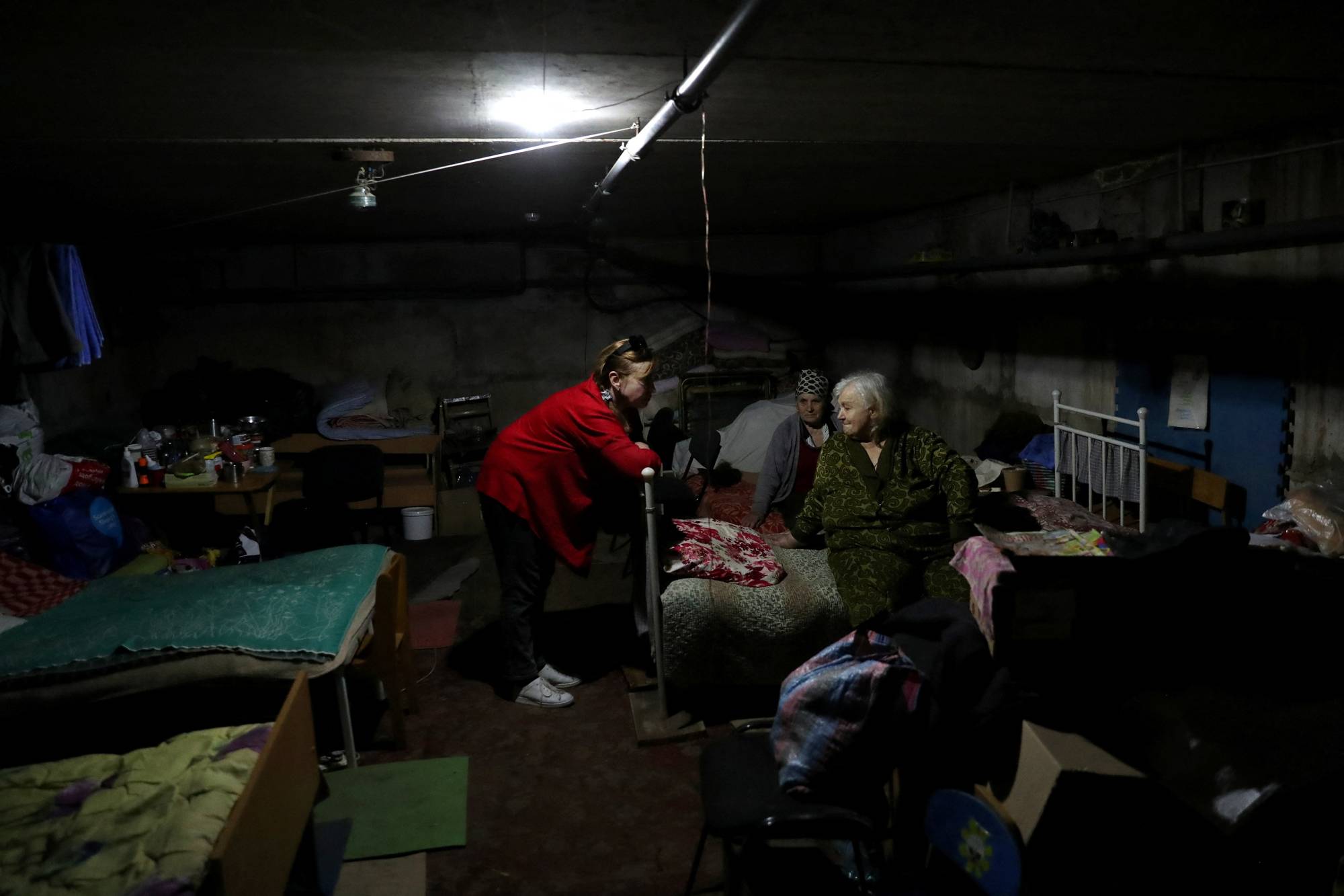 Nataliia Kyrychenko, a member of the Vilkhivka village council, who was detained by Russian soldiers while her village of Kutuzivka was occupied, talks to local residents living inside an underground shelter on June 1. | REUTERS