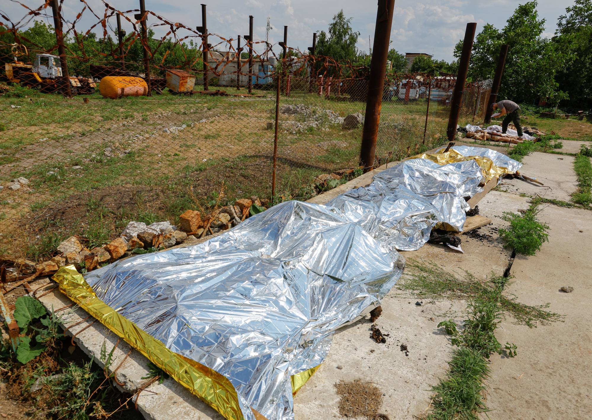 Burnt bodies of detainees are covered following an explosion at a Russian-held detention center in Olenivka, Ukraine, on Friday.   | REUTERS