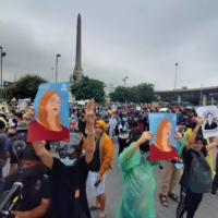 Demonstrators against the Thai regime gather in Bangkok in October 2020, with one of them (right) holding a drawing of an activist who went missing in Cambodia. | NISHINIPPON SHIMBUN
