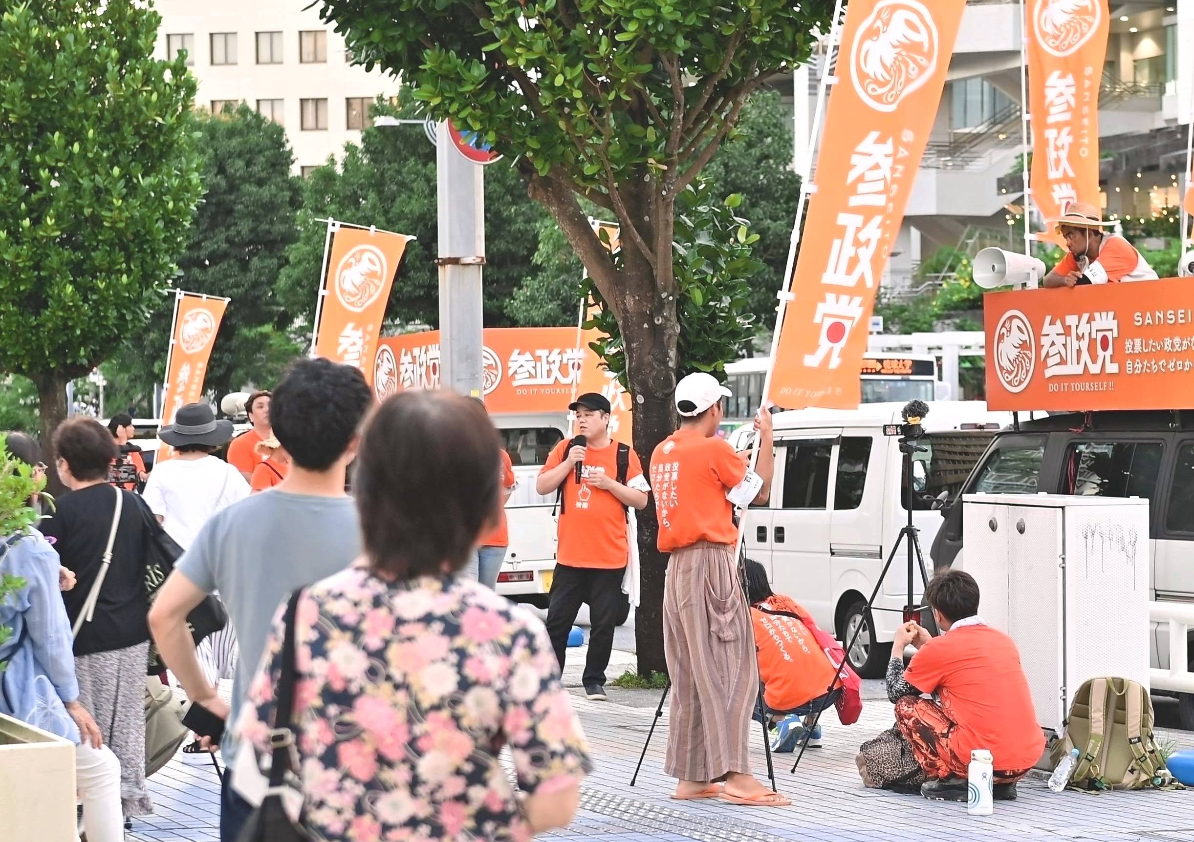 People listen to a speech by Sanseito members in Naha on July 8. | THE OKINAWA TIMES