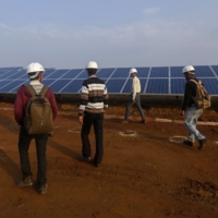 Employees inspect a solar power plant in Neemuch, Madhya Pradesh, India, in 2014. | BLOOMBERG