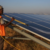 A worker washes photovoltaic panels at a solar farm in Pavagada, Karnataka, India, in February. | BLOOMBERG