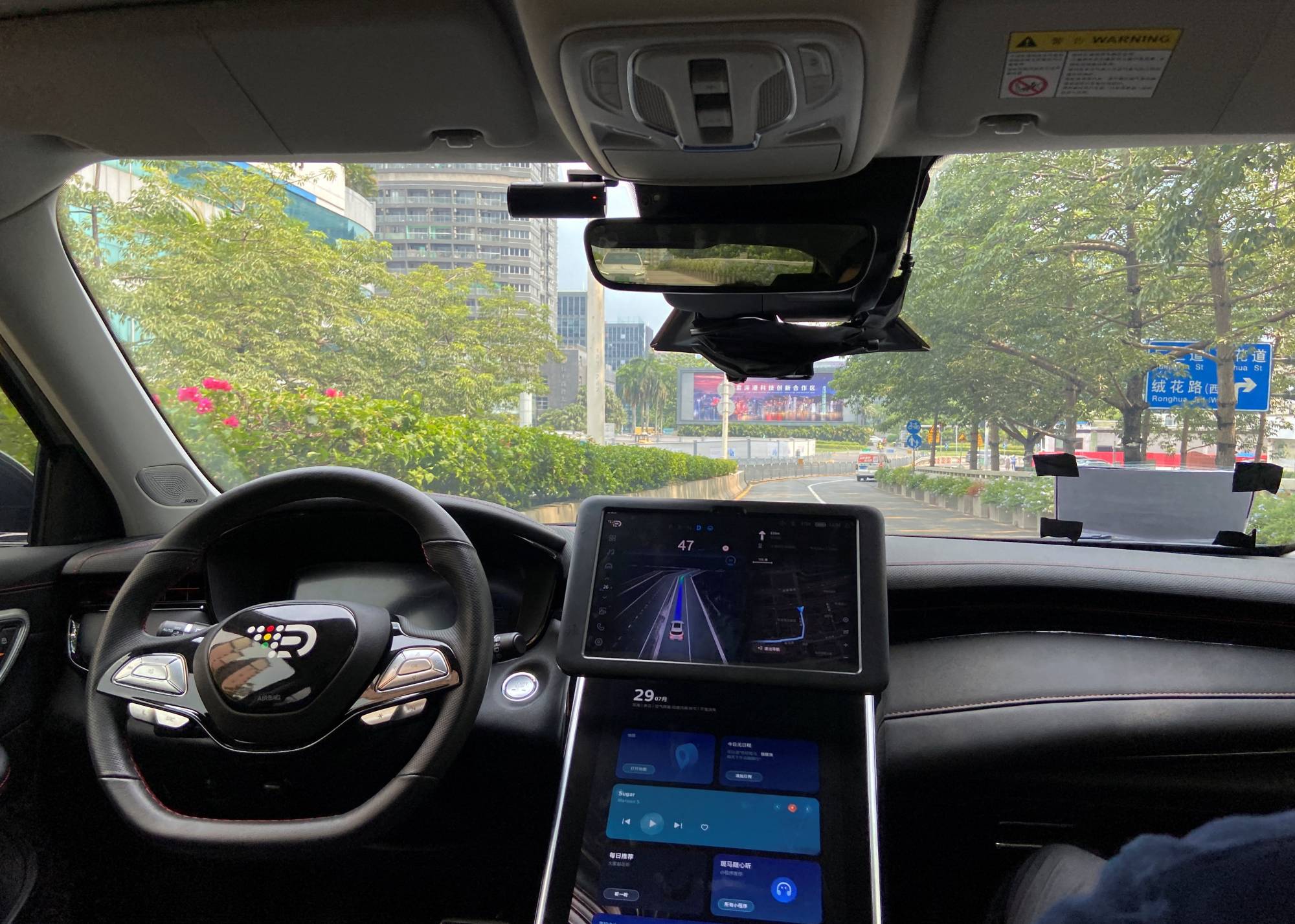 A safety driver sits in the passenger seat as a car with an autonomous driving system developed by DeepRoute.ai drives itself down a street in Shenzhen, China. | REUTERS
