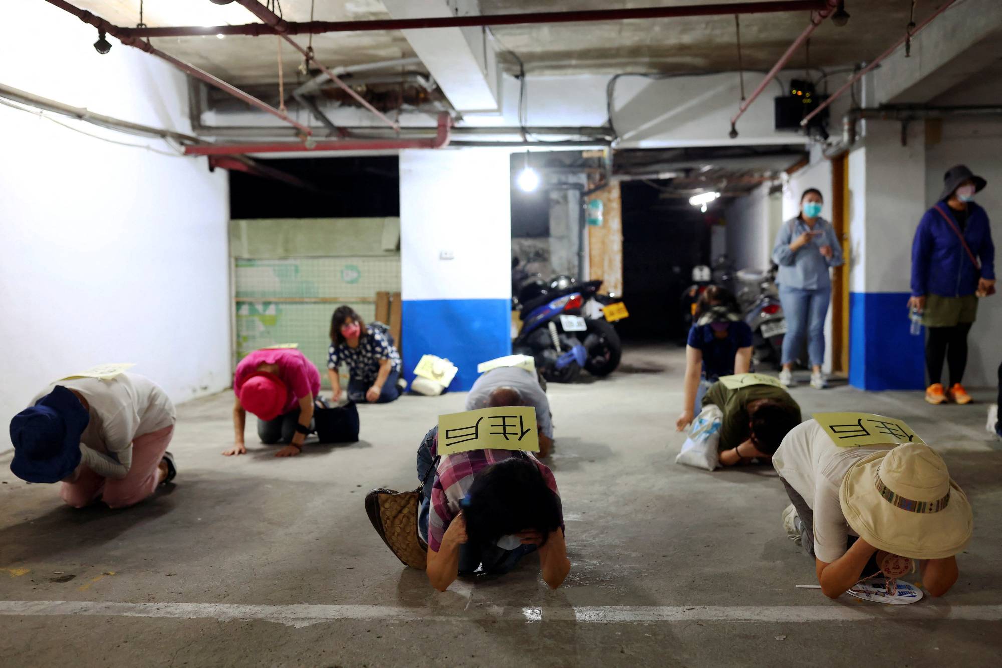 People practice for drill in a basement parking lot that will be used as an air-raid shelter in the event of an attack, in Taipei on July 22. | REUTERS