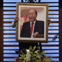 A believer carries a portrait of Unification Church founder Sun Myung Moon toward an altar at the headquarters of the group\'s Japan branch in Tokyo on Sept. 3, 2012, the day of his death. Since the assassination of former Prime Minister Shinzo Abe, ties between the church and the nation’s lawmakers, including those from the ruling Liberal Democratic Party, have come under scrutiny. | REUTERS