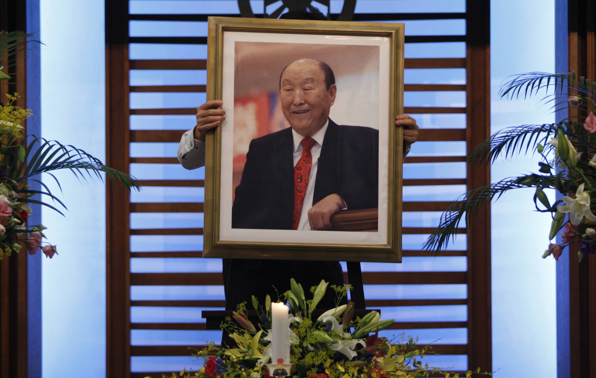 A believer carries a portrait of Unification Church founder Sun Myung Moon toward an altar at the headquarters of the group's Japan branch in Tokyo on Sept. 3, 2012, the day of his death. Since the assassination of former Prime Minister Shinzo Abe, ties between the church and the nation’s lawmakers, including those from the ruling Liberal Democratic Party, have come under scrutiny. | REUTERS