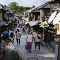 Visitors stroll along a commercial street in Kyoto. Domestic travel is booming as people enjoy their first restriction-free summer since 2019 and as still-tight border rules keep away the hordes of foreign visitors that typically crowd popular attractions. | BLOOMBERG