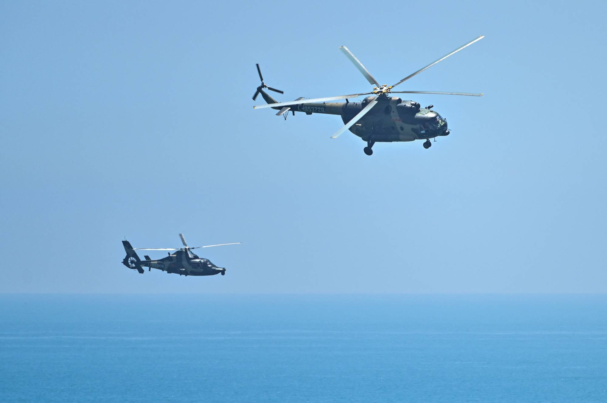 Chinese military helicopters fly past Pingtan island on Thursday. | AFP-JIJI