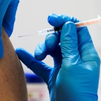 A local resident receives a COVID-19 booster shot at a mass vaccination center in Tokyo. Japan plans to roll out a new type of COVID-19 vaccine considered effective against the omicron variant as early as October. | POOL / VIA REUTERS