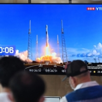 A TV at a railway station in Seoul shows live footage of a SpaceX Falcon 9 rocket launching with South Korea\'s first lunar orbiter Danuri onboard. | AFP-JIJI