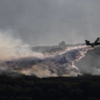 An aircraft drops water over burning forests near Vogue, Ardeche, in southern France on July 27. | AFP-JIJI