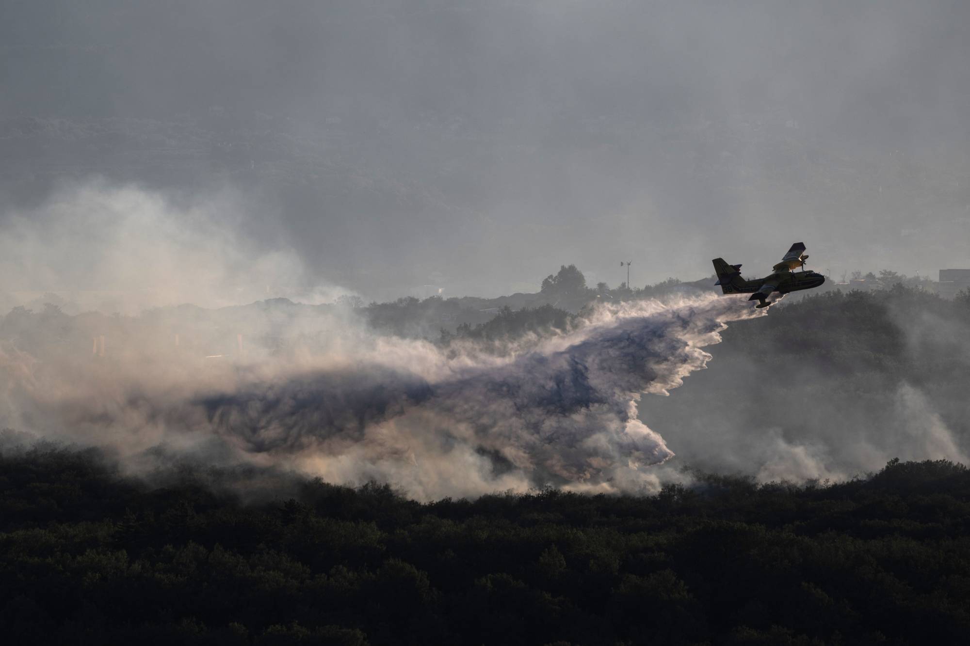 An aircraft drops water over burning forests near Vogue, Ardeche, in southern France on July 27. | AFP-Jiji