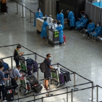 Travelers heading to quarantine in the arrival hall at Hong Kong International Airport in Hong Kong on Monday. | BLOOMBERG
