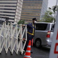 A police officer conducts vehicle checks near the U.S. Embassy in Tokyo in May. | KYODO
