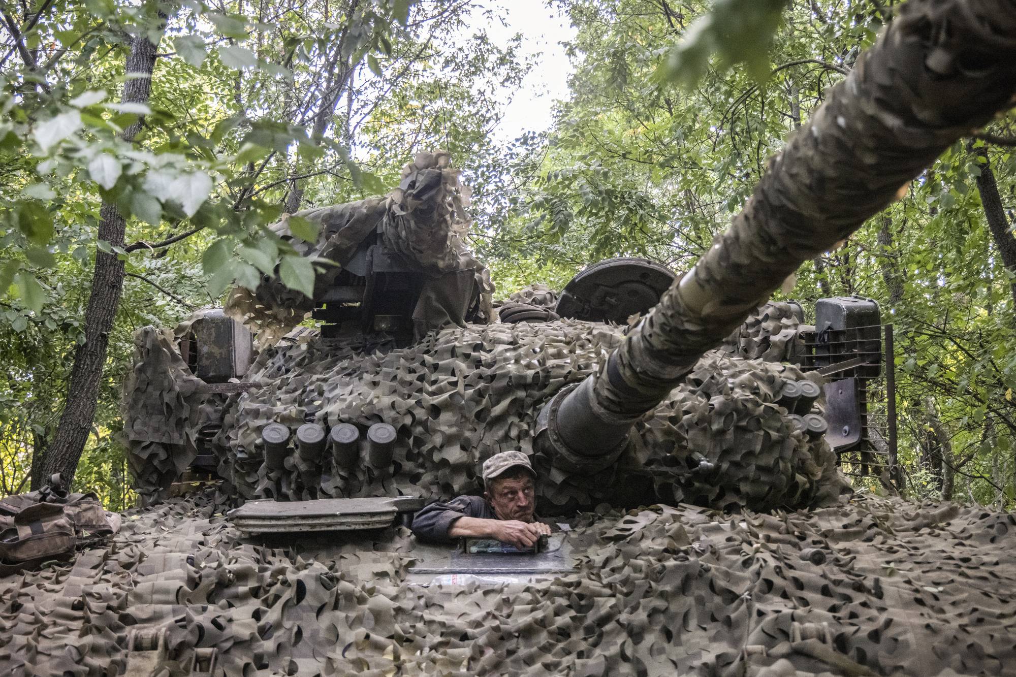 A Ukrainian soldier climbs out of a tank at a camouflaged frontline position after completing a mission in Kherson region of Ukraine, on July 28. | David Guttenfelder / The New York Times