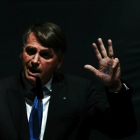 Brazilian President Jair Bolsonaro gestures while mocking the former Brazilian President Luiz Inacio Lula da Silva during the opening of the National Agro Meeting in Brasilia on Wednesday. | REUTERS