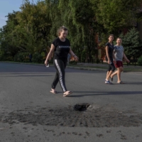 People walk next to a crater left by shelling from Russian forces in Marhanets, Ukraine.  | AFP-JIJI