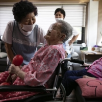 Park Ok-sun with a caregiver at the House of Sharing | WOOHAE CHO / THE NEW YORK TIMES