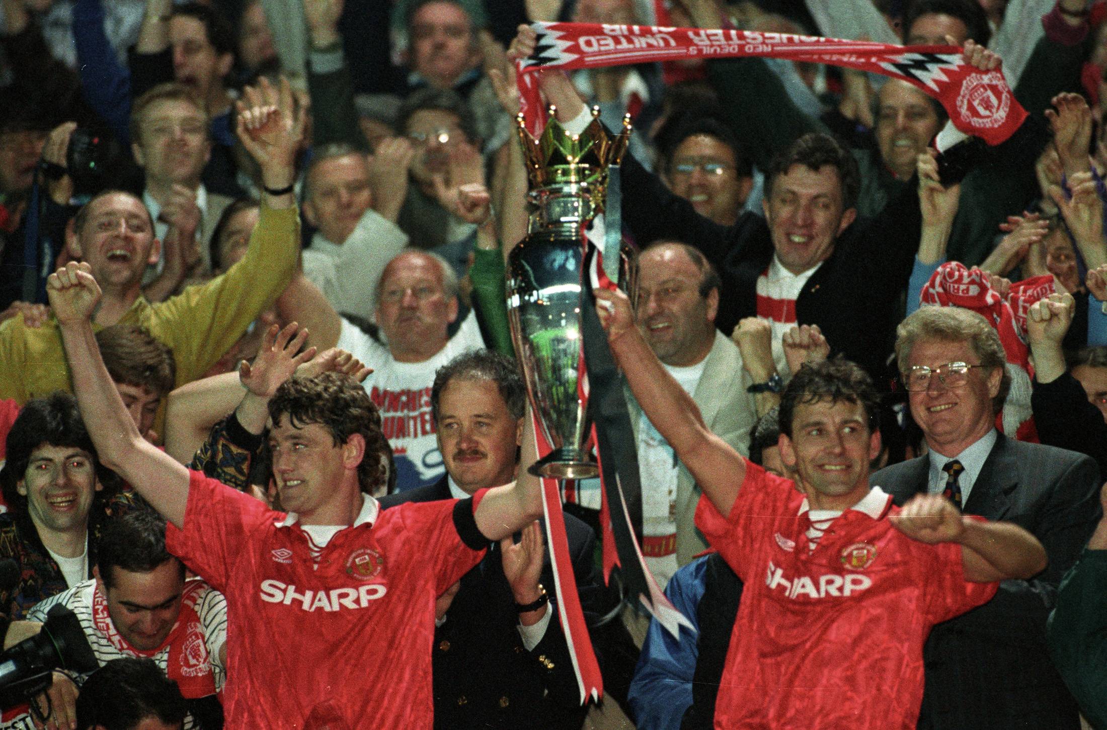 Manchester United captain Steve Bruce (left) and Brian Robson hold the trophy aloft after winning the Premier League's inaugural season in Manchester on May 3, 1993. | REUTERS