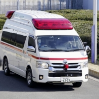An ambulance carrying Japanese nationals who returned from Wuhan in 2020. Almost three years later Japan is in the midst of a seventh wave of COVID-19 infections, hitting a record number of weekly cases of ambulances struggling to find a hospital for patients. | KYODO 
