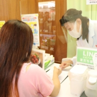 A woman is tested with an antigen test at a pharmacy in Tokyo on Aug. 1. | KYODO