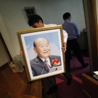 A church member carries a portrait of Sun Myung Moon toward an altar during Sun\'s memorial mass at Japan\'s Unification Church headquarters in Tokyo in September 2012. | REUTERS