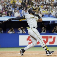 The Tigers\' Mel Rojas Jr. connects on a three-run home run against the Swallows at Jingu Stadium on Thursday. | KYODO