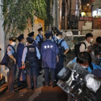 Police officers are seen near the site where a girl apparently stabbed a mother in her 50s and her young daughter in Tokyo\'s Shibuya Ward on Saturday. | KYODO　